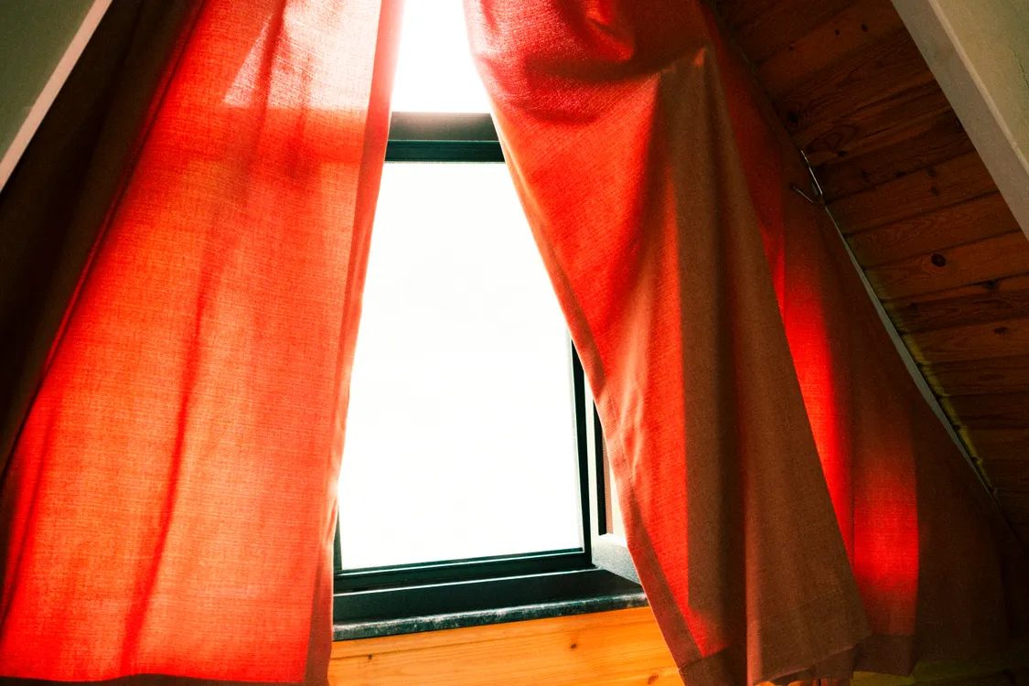 Warm sunlight through red curtains at a window